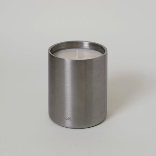 brushed stainless steel cylindrical container with a candle inside on a light gray background